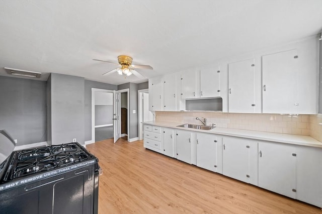 84 Tremont St, Taunton, MA 02780 - kitchen with black range with gas cooktop, a sink, light countertops, and white cabinets