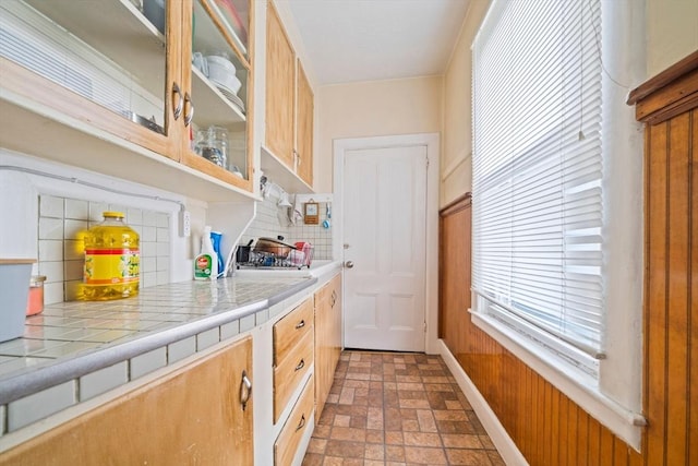 84 Tremont St, Taunton, MA 02780 - kitchen featuring backsplash, glass insert cabinets, tile countertops, baseboards, and wooden walls