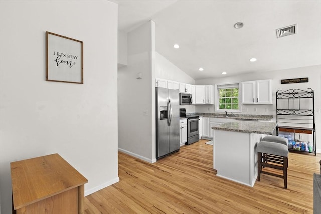 189 Progresso Ave, Woonsocket, RI 02895 - kitchen with appliances with stainless steel finishes, white cabinets, a kitchen bar, light wood-type flooring, and a center island
