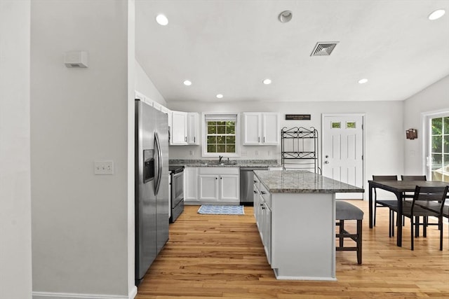 189 Progresso Ave, Woonsocket, RI 02895 - kitchen with appliances with stainless steel finishes, a kitchen breakfast bar, a center island, white cabinets, and light wood-type flooring
