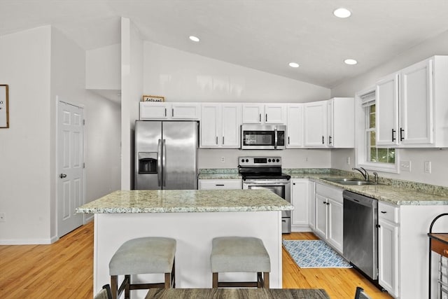 189 Progresso Ave, Woonsocket, RI 02895 - kitchen with stainless steel appliances, lofted ceiling, a breakfast bar area, white cabinetry, and light wood-style floors