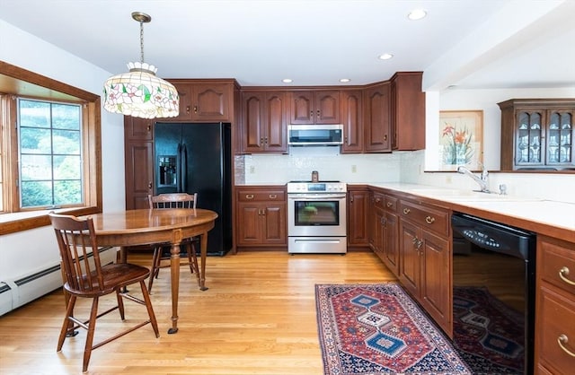 kitchen featuring hanging light fixtures, sink, light hardwood / wood-style floors, black appliances, and decorative backsplash