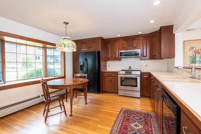 kitchen featuring black appliances, baseboard heating, light wood-type flooring, decorative light fixtures, and sink