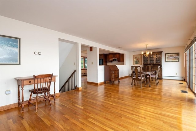 living room featuring light wood-type flooring, a baseboard heating unit, and an inviting chandelier