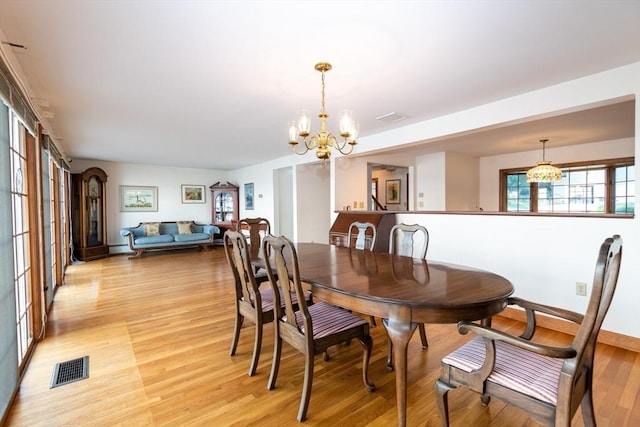 dining area with light hardwood / wood-style flooring and a chandelier