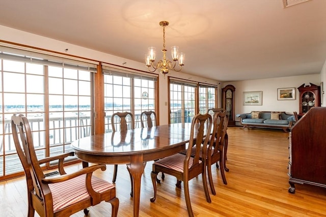 dining space with light wood-type flooring and a notable chandelier