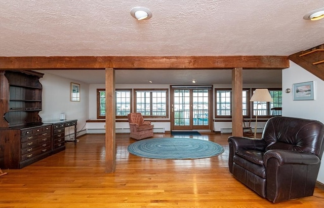 living room with a baseboard radiator, light hardwood / wood-style floors, a textured ceiling, and beam ceiling