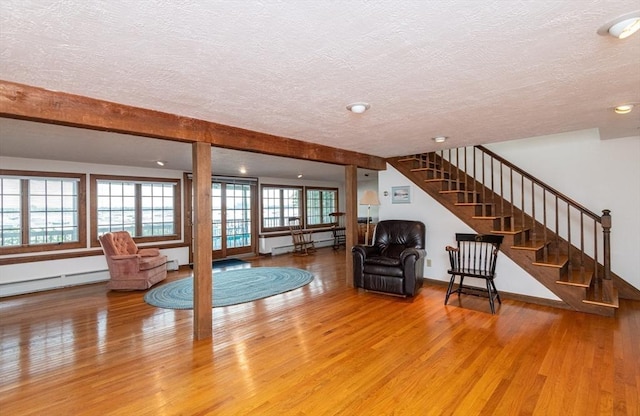 unfurnished living room with hardwood / wood-style floors, a textured ceiling, and a baseboard radiator