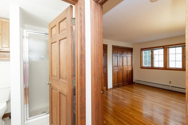 hallway with light wood-type flooring and a baseboard radiator