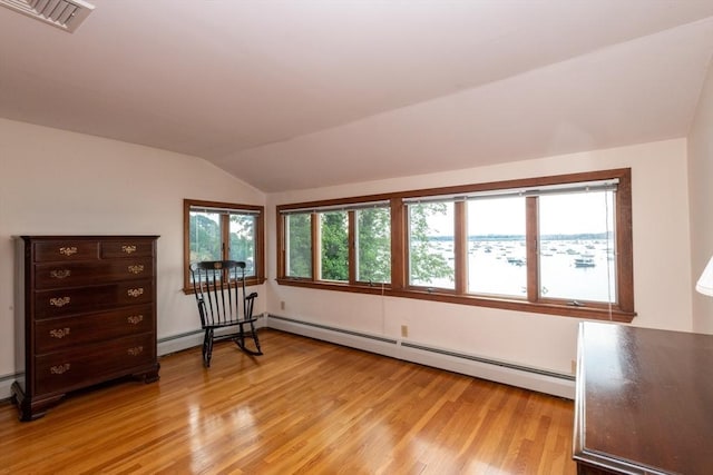 interior space with light wood-type flooring, vaulted ceiling, and a baseboard radiator