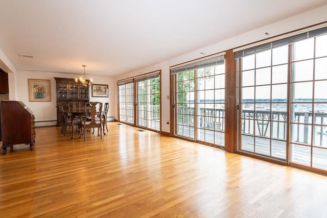 dining space featuring baseboard heating, a notable chandelier, and light wood-type flooring