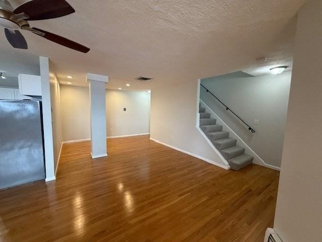 basement featuring refrigerator, ceiling fan, a textured ceiling, wood finished floors, and stairs