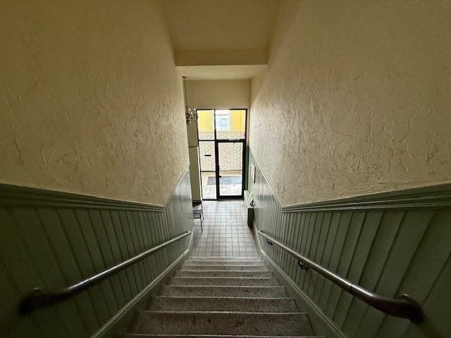 stairs featuring a wainscoted wall and a textured wall