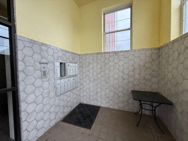 bathroom featuring mail area, tile walls, and wainscoting