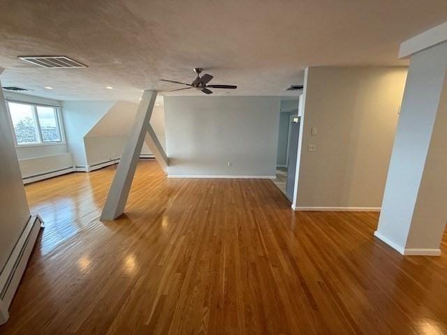 interior space featuring a baseboard radiator, wood finished floors, visible vents, and baseboards