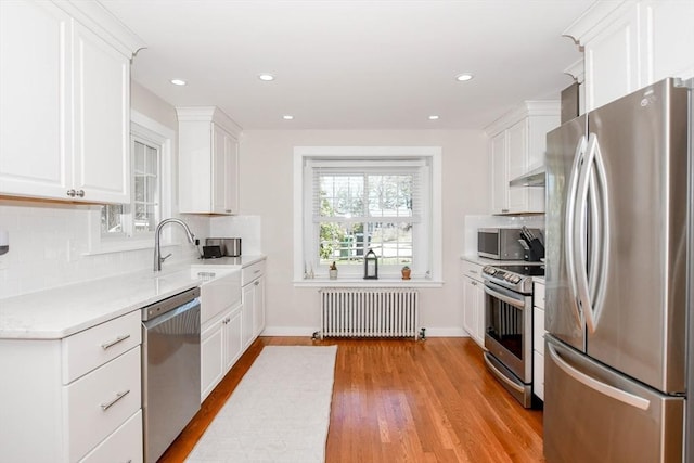 54 Converse Rd, Marion, MA 02738 - kitchen with stainless steel appliances, radiator heating unit, white cabinets, decorative backsplash, and recessed lighting