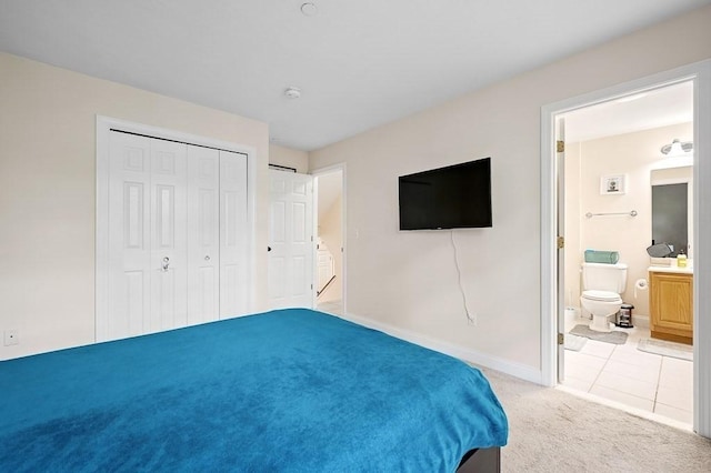 bedroom featuring light colored carpet, baseboards, a closet, ensuite bathroom, and light tile patterned floors