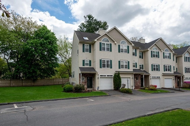 multi unit property featuring an attached garage, driveway, a chimney, and brick siding