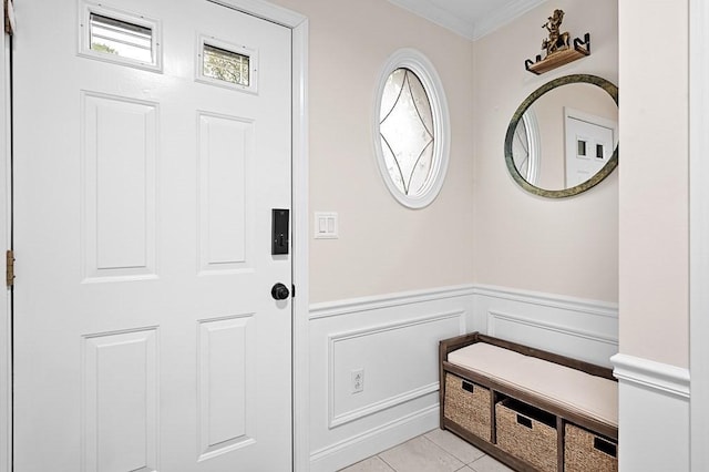 foyer featuring ornamental molding, wainscoting, a decorative wall, and light tile patterned floors