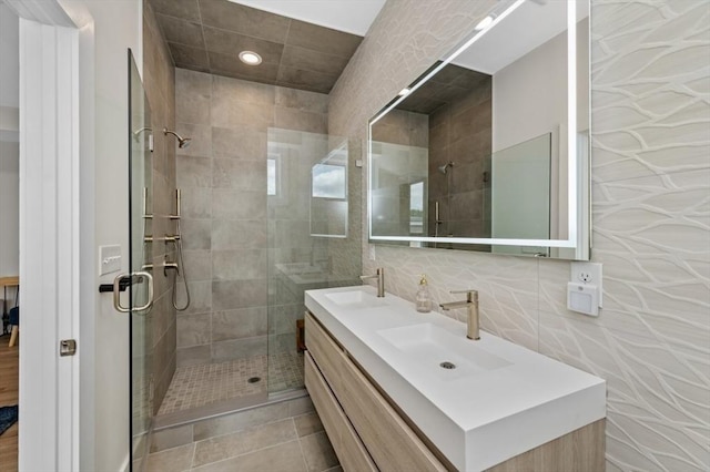 full bath with tile walls, a shower stall, double vanity, and recessed lighting