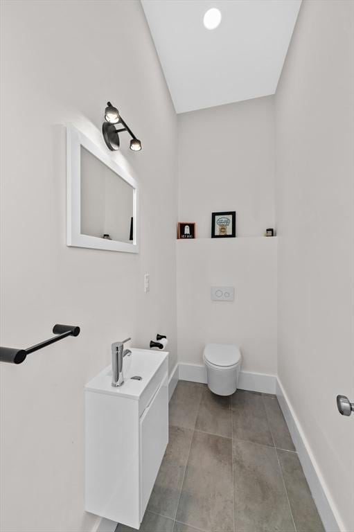 bathroom with baseboards, vanity, tile patterned flooring, and toilet