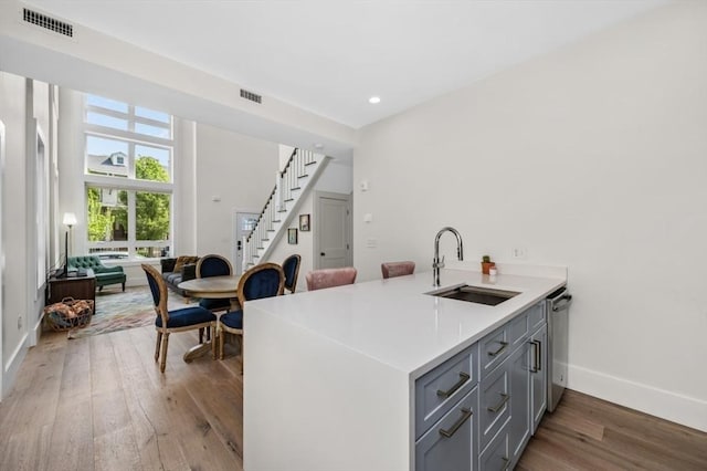 kitchen featuring a sink, gray cabinetry, light wood finished floors, baseboards, and light countertops