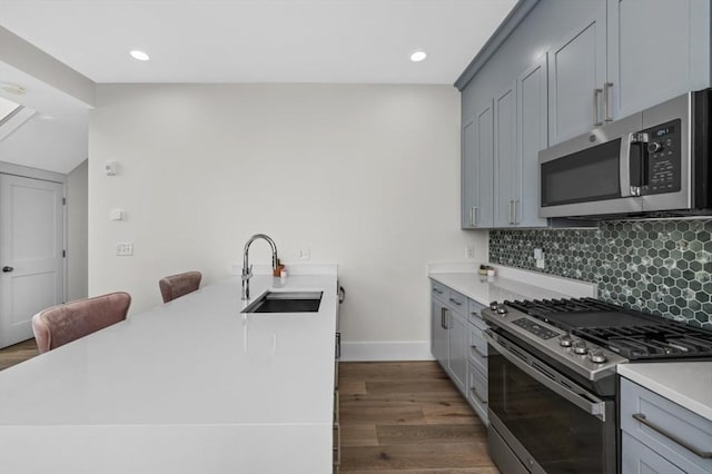kitchen featuring stainless steel appliances, a sink, a peninsula, light countertops, and decorative backsplash