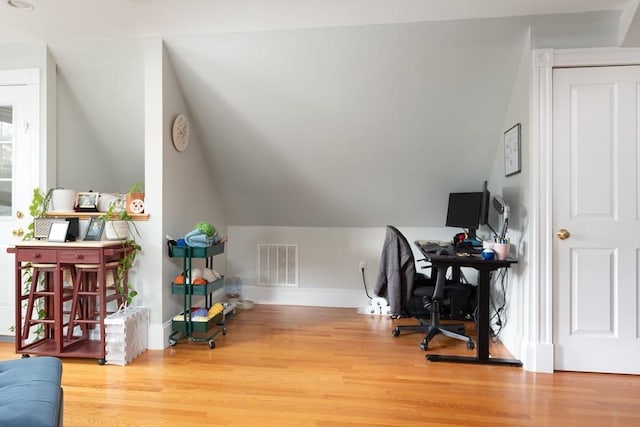 home office featuring baseboards, visible vents, wood finished floors, and vaulted ceiling