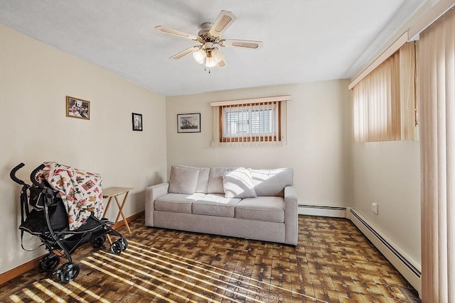 living area featuring a baseboard radiator, baseboards, and a ceiling fan