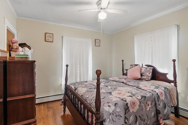 bedroom with wood finished floors, baseboard heating, and ornamental molding