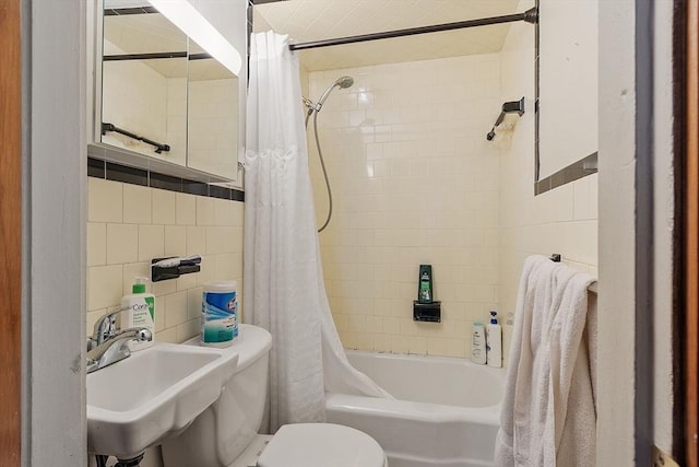 full bathroom featuring toilet, shower / bathtub combination with curtain, tile walls, and a sink