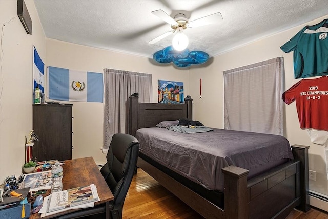 bedroom featuring ceiling fan, baseboard heating, wood finished floors, and a textured ceiling