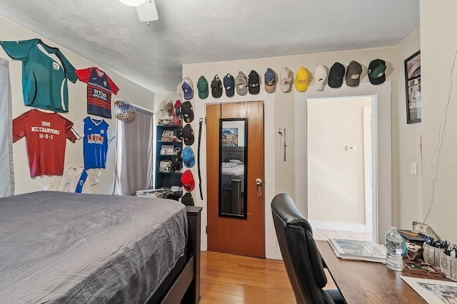 bedroom with a ceiling fan, light wood finished floors, and a textured ceiling