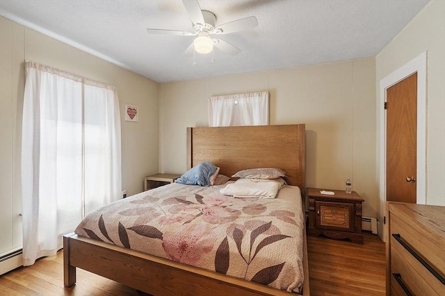 bedroom with a ceiling fan, light wood-style floors, and a baseboard radiator