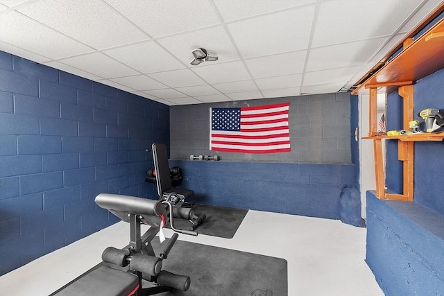 workout area with a drop ceiling and concrete block wall