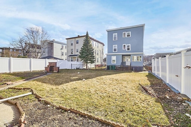 rear view of property with entry steps, a yard, and a fenced backyard