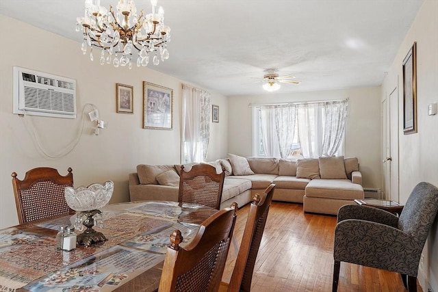 living area featuring a baseboard heating unit, a ceiling fan, light wood finished floors, and a wall mounted AC