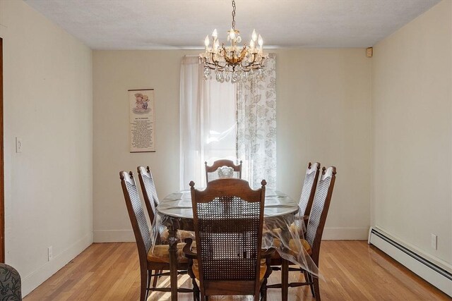 dining area featuring an inviting chandelier, light wood-style flooring, baseboards, and a baseboard radiator