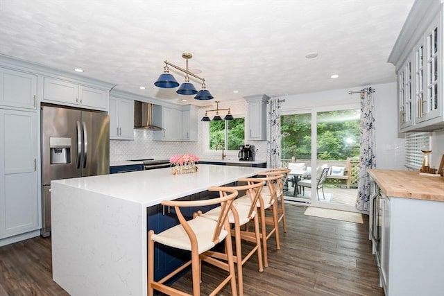 8 Highland View Ave, Mattapoisett, MA 02739 - kitchen featuring stainless steel fridge, wall chimney exhaust hood, light countertops, tasteful backsplash, and a center island