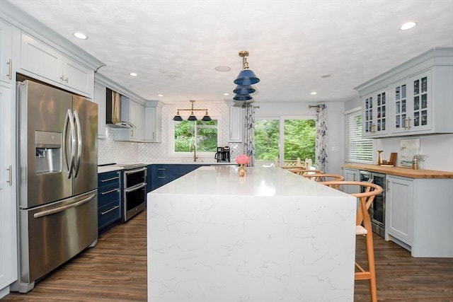 8 Highland View Ave, Mattapoisett, MA 02739 - kitchen with appliances with stainless steel finishes, wall chimney range hood, beverage cooler, dark wood-style floors, and a breakfast bar