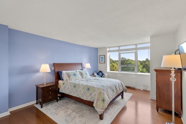 bedroom featuring radiator heating unit and hardwood / wood-style floors