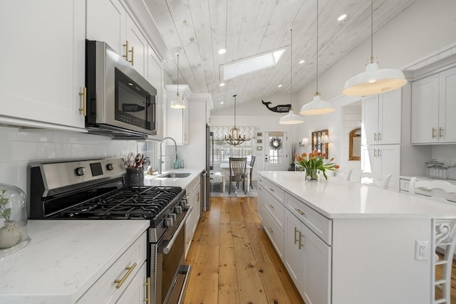 16 Walking Stick, Plymouth, MA 02360 - kitchen featuring appliances with stainless steel finishes, a skylight, light wood-type flooring, a kitchen island, and vaulted ceiling
