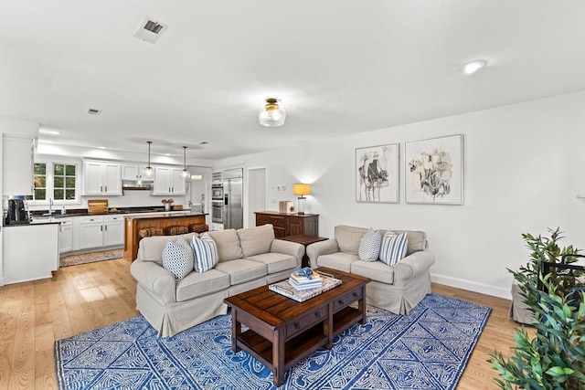 living room with sink and light wood-type flooring