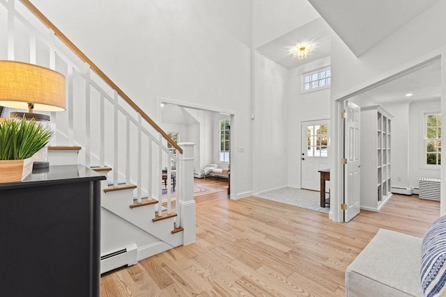 foyer entrance featuring light hardwood / wood-style flooring, a healthy amount of sunlight, and baseboard heating