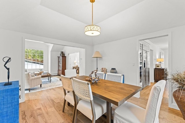 dining space featuring vaulted ceiling, light hardwood / wood-style floors, and a baseboard radiator