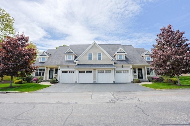 shingle-style home featuring an attached garage, driveway, and a front lawn