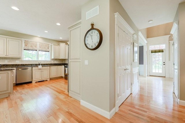 corridor featuring light wood finished floors, a sink, baseboards, and recessed lighting