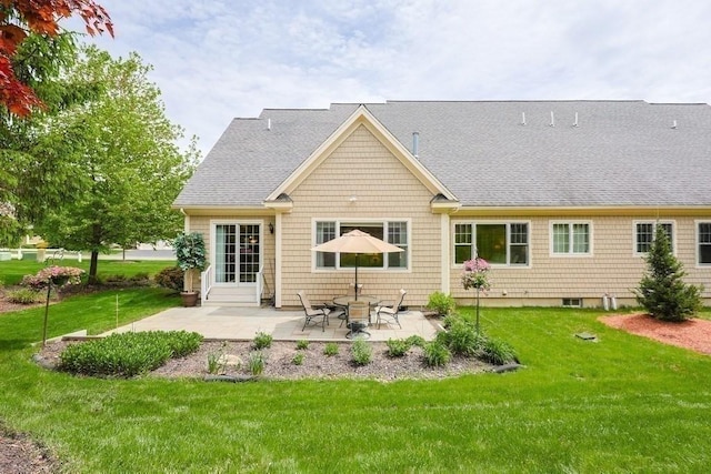 rear view of property with a lawn, a patio area, and a shingled roof