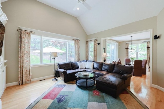 living room with wood finished floors, healthy amount of natural light, ceiling fan, baseboards, and high vaulted ceiling