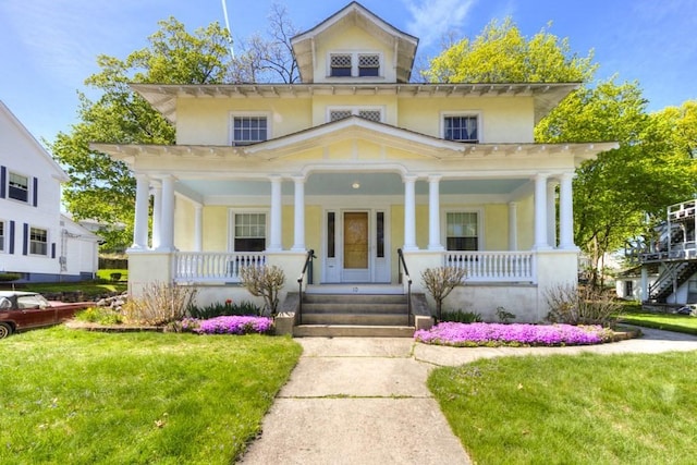italianate-style house featuring covered porch, a front yard, and stucco siding